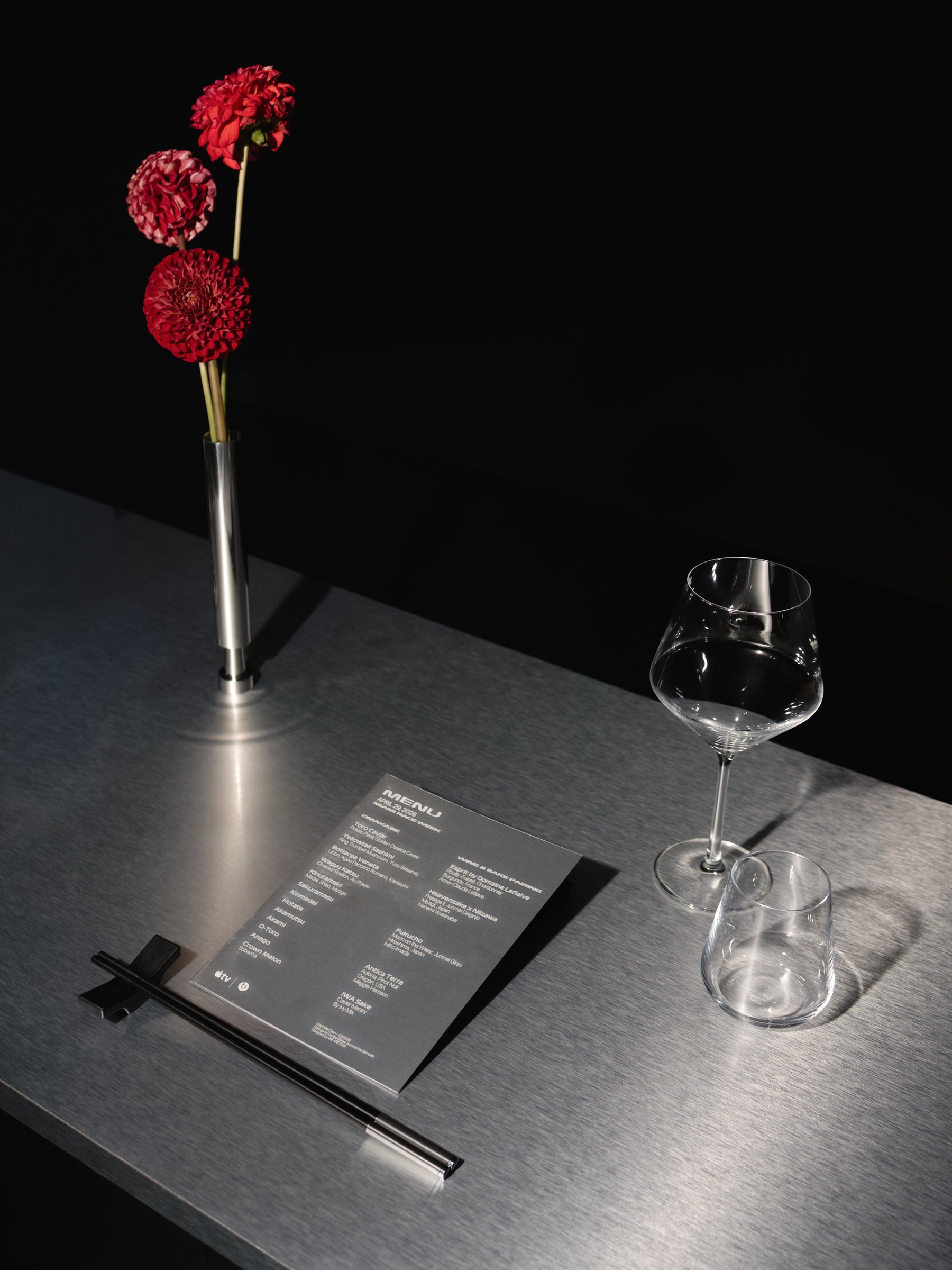Menu card with red dahlias and a wine glass at the Apple TV x Beats Miami Race Weekend dinner, photographed by Alicia Valdez