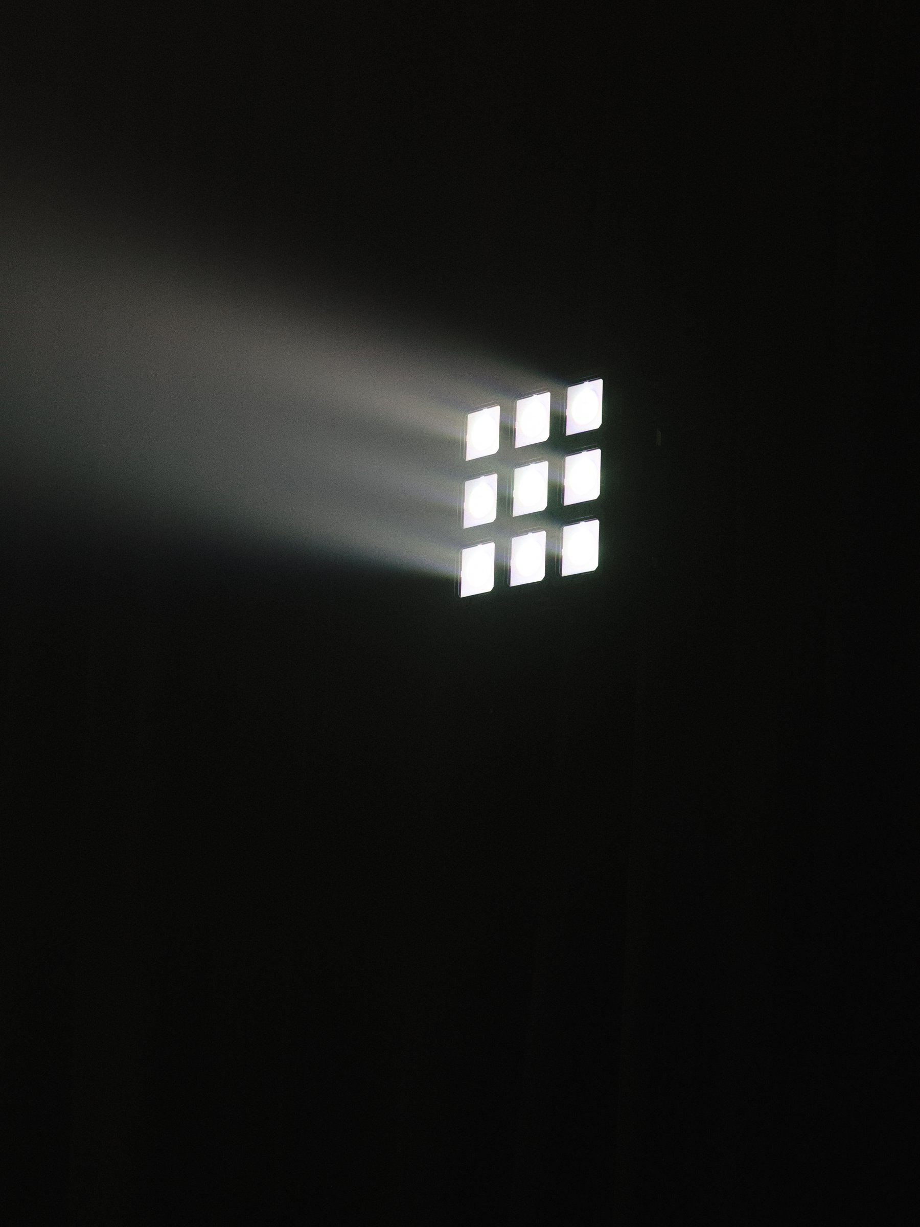 Theatrical stage light cutting through darkness above the Apple TV x Beats Miami dinner, photographed by Alicia Valdez
